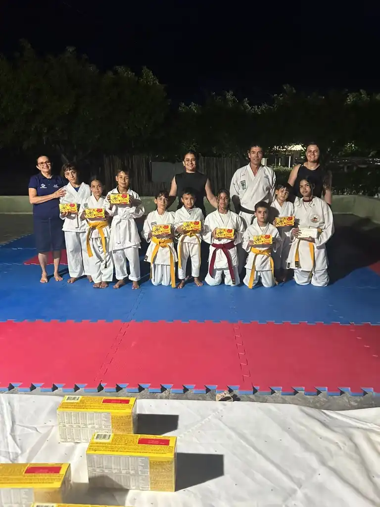 Turma de karatê com instrutores posando no tatame após atividade comemorativa
