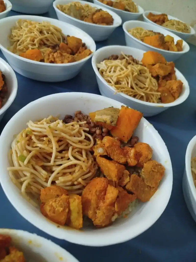 Marmitas com macarrão, frango temperado, abóbora e feijão alinhadas para distribuição